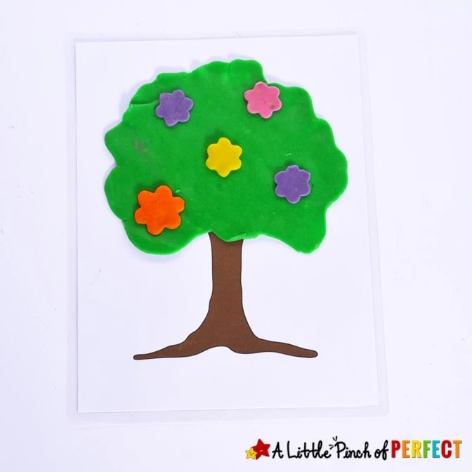 Spring playdough mat free printable that looks like a tree with a playdough top and pink, yellow, orange, and purple flowers.