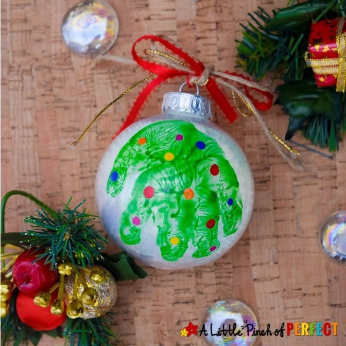 Make an adorable handprint Christmas tree ornament with our easy step by step directions and video tutorial. The ornaments turn out so cute and make great decorations, gifts, and keepsakes. #christmas #ornaments #craft #kidscrafts