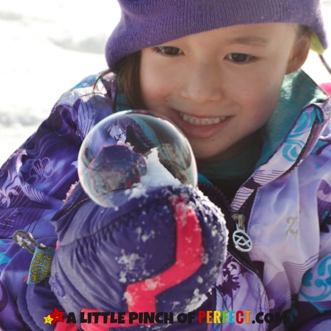 Child holding a bubble in winter