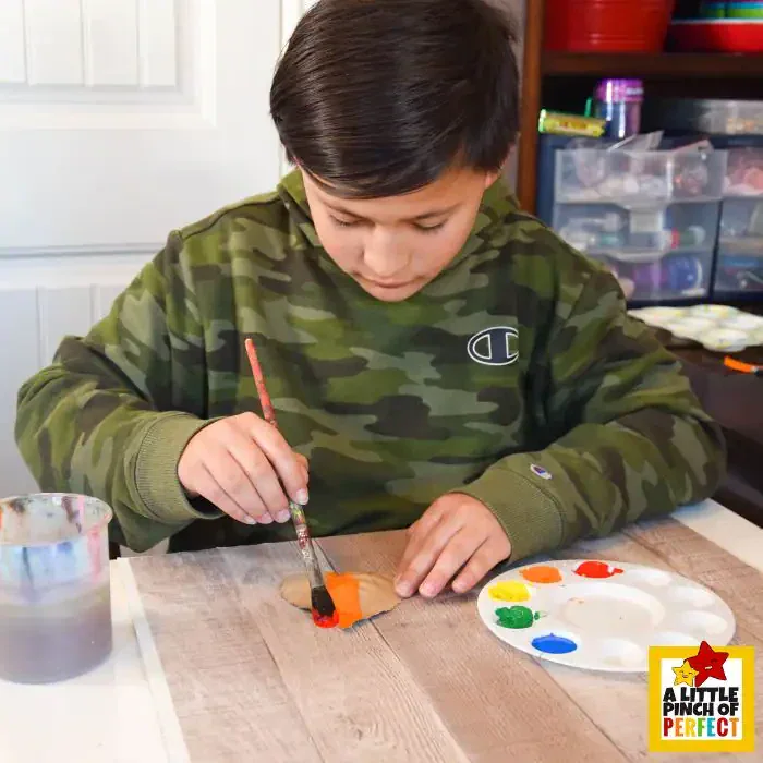 Child painting a leaf to make a Pincecone Leaf Turkey Craft