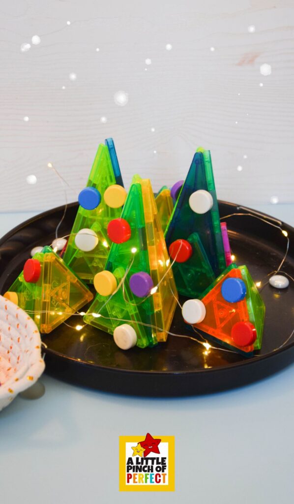 Magna Tile Christmas Tree Decorating Activity: Fairy lights shining through translucent Magna-Tiles shaped like a Christmas tree.