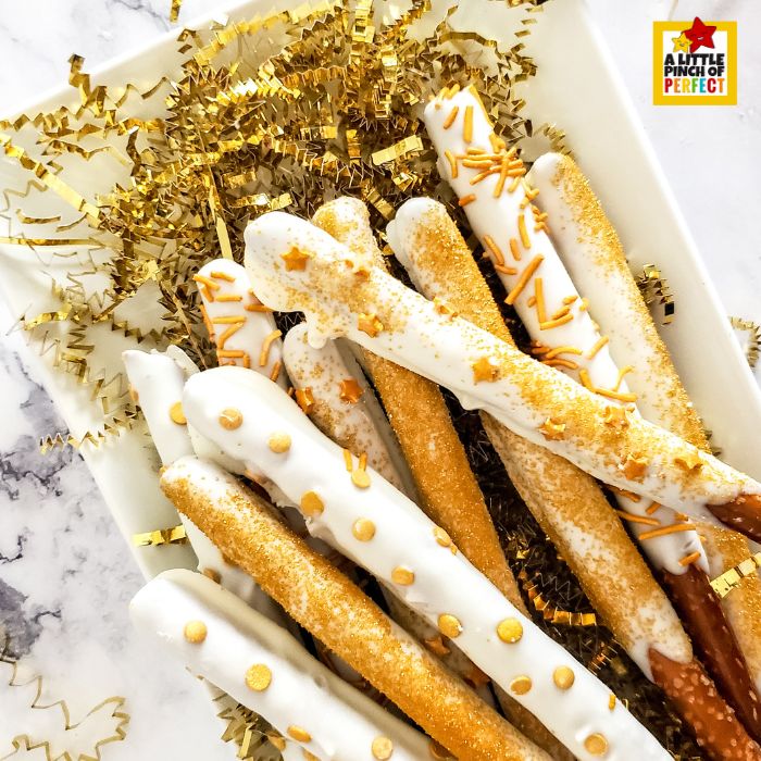 Chocolate-covered pretzel rod sparklers with gold sprinkles for New Year’s Eve