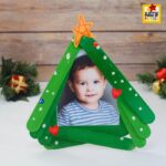 Popsicle stick Christmas tree used as a kid-made photo frame for a holiday craft.