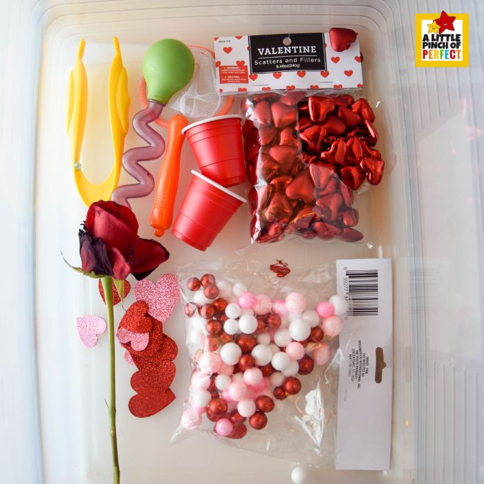 Love Potion Pour & Play Valentine Sensory Bin supplies including foam hearts, plastic hearts, rose petals, cups, and water tools