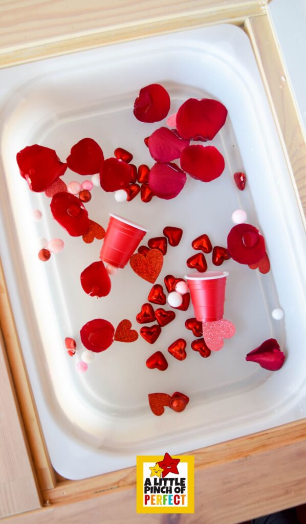Love Potion Pour & Play Valentine Sensory Bin showing potion cups, scoops, and heart-themed water play