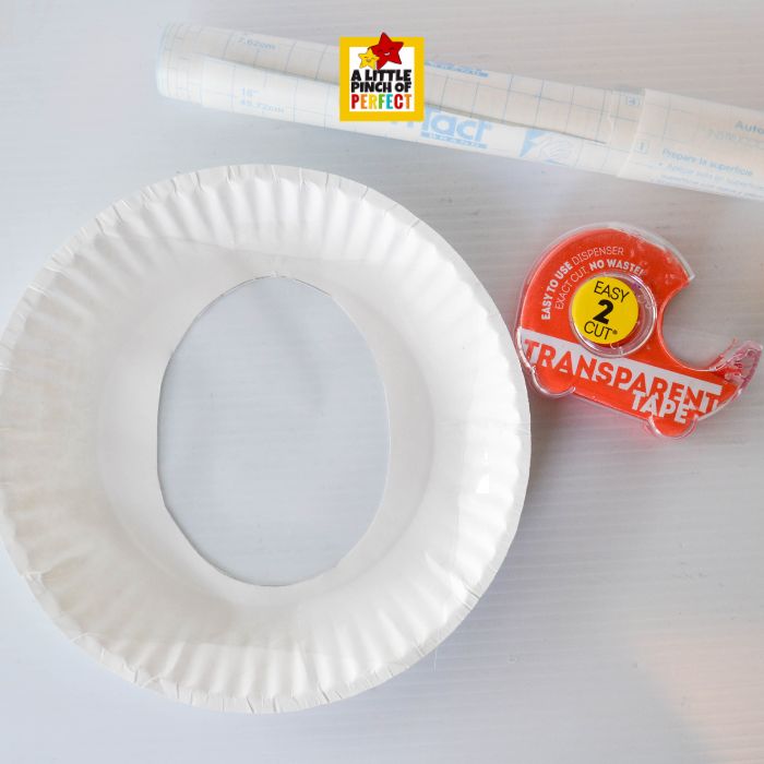 What’s Inside the Easter Egg? Easter Egg Suncatcher Craft for Kids (Free Template) – attaching clear contact paper to back of paper plate egg opening for sticky surface