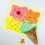 Melted Ice Cream Puffy Paint Art Project for Kids decorating fluffy painted ice cream with paper sprinkles, chocolate chips, marshmallows, and colorful toppings before the paint dries.