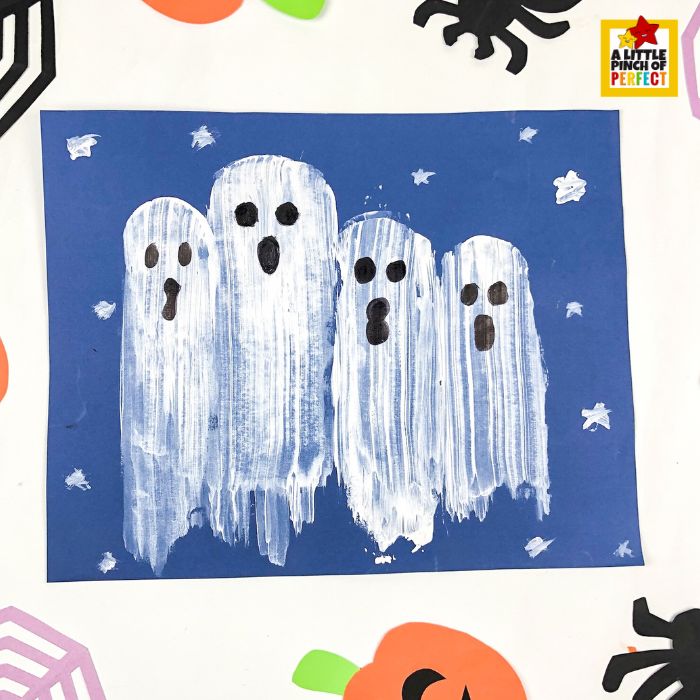 potato painted ghosts come to life with just a little black paint for eyes and mouths &mdash; this finished Halloween kids craft on blue paper features a sweet ghost family surrounded by white stars, made using potato stamps and acrylic paint.