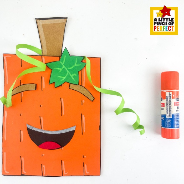 Pumpkin Paper Bag Craft with Template &mdash; a fun way to bring your paper bag pumpkin to life by adding the cut paper face pieces including eyebrows, mouth, and lip along with the green leaf, brown stem, and curly ribbon tendrils, making it a great Halloween kids craft or seasonal treat bag.